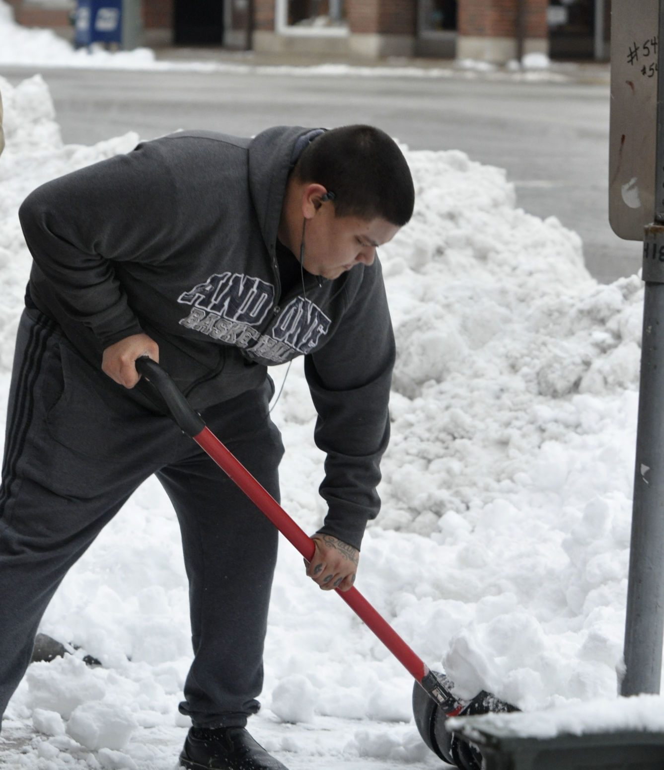 Juan Grisales helps to shovel some snow in front of some businesses on Broad Street in Lake Genva
